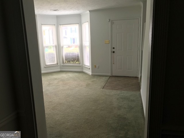 foyer entrance featuring a textured ceiling and light colored carpet