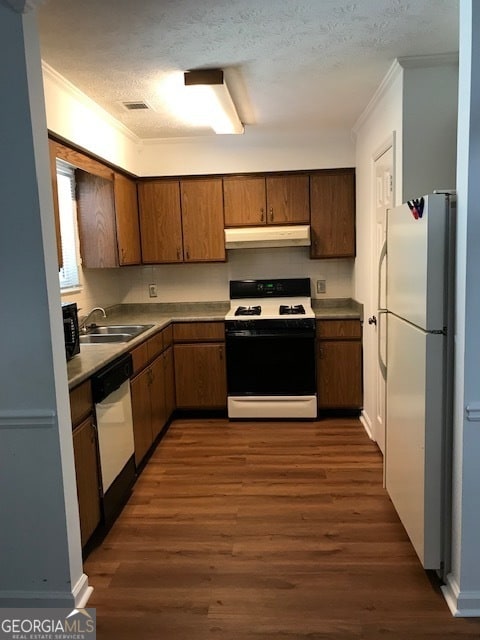 kitchen featuring crown molding, dark wood-type flooring, sink, and white appliances