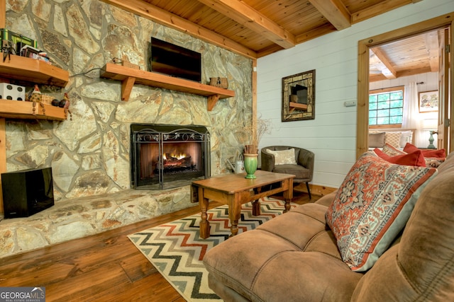 living room featuring wood-type flooring, a fireplace, beamed ceiling, and wooden ceiling