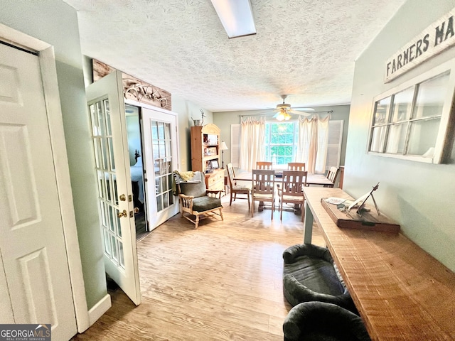 interior space featuring ceiling fan, french doors, a textured ceiling, and hardwood / wood-style flooring