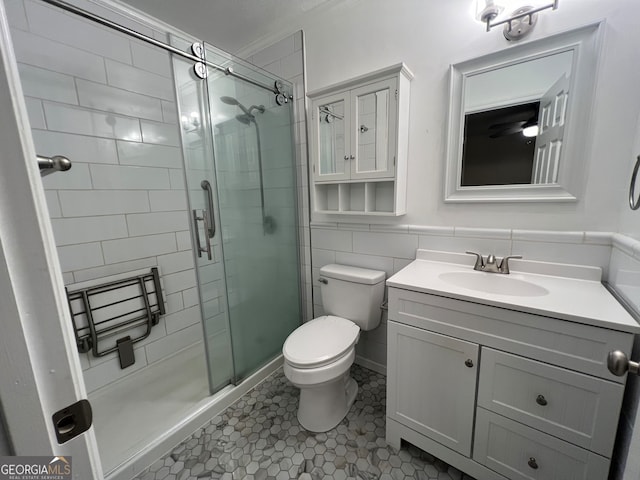 bathroom with tile walls, toilet, tile patterned floors, vanity, and a shower with shower door