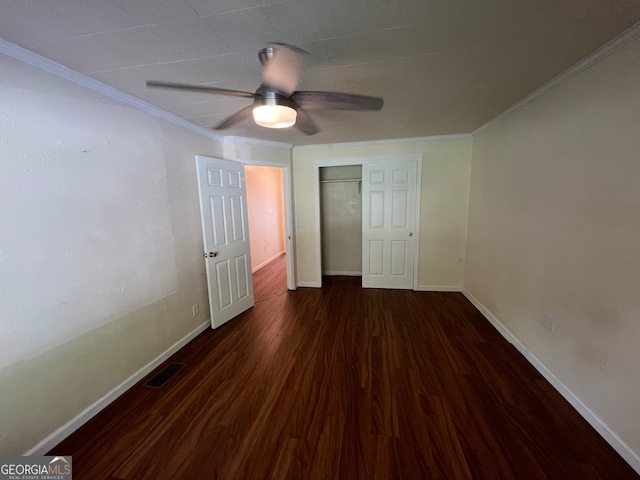 unfurnished bedroom featuring ceiling fan, crown molding, dark hardwood / wood-style flooring, and a closet