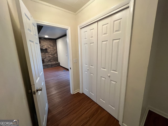 corridor featuring crown molding, wood-type flooring, and brick wall