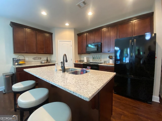 kitchen featuring an island with sink, dark hardwood / wood-style floors, sink, and black appliances