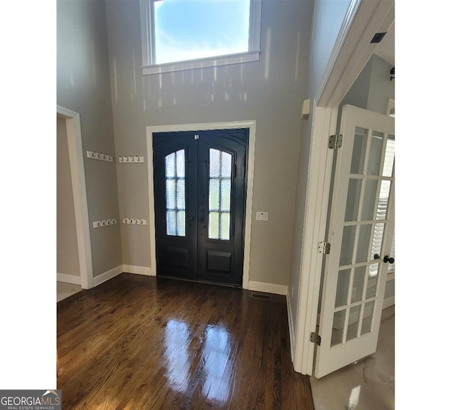 entrance foyer featuring a towering ceiling, dark hardwood / wood-style flooring, and french doors