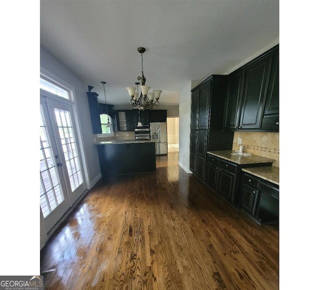 kitchen featuring pendant lighting, a notable chandelier, backsplash, stainless steel fridge with ice dispenser, and dark wood-type flooring