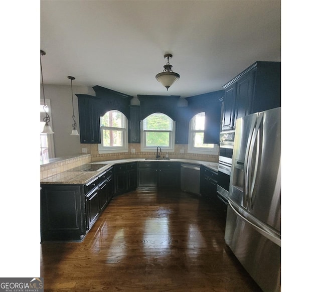 kitchen with dark hardwood / wood-style floors, pendant lighting, stainless steel appliances, sink, and kitchen peninsula