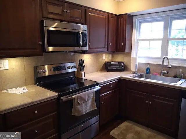 kitchen with appliances with stainless steel finishes, decorative backsplash, and sink