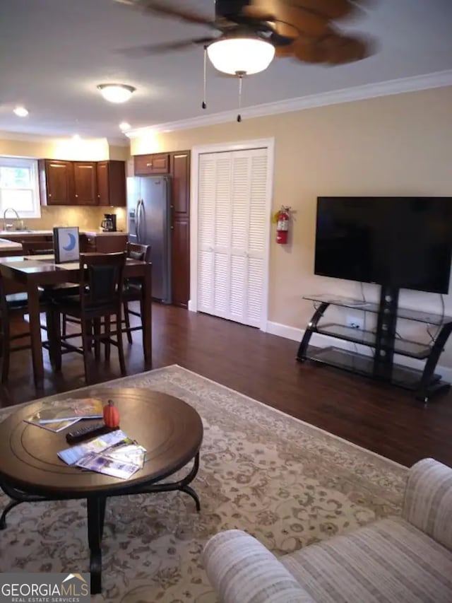 living room featuring ceiling fan, sink, ornamental molding, and dark hardwood / wood-style flooring