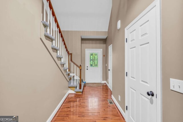 foyer with stairway, wood finished floors, visible vents, and baseboards