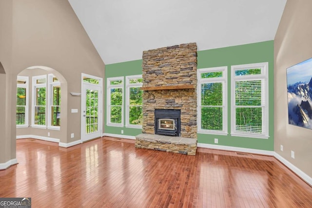 unfurnished living room with hardwood / wood-style floors, a healthy amount of sunlight, and high vaulted ceiling