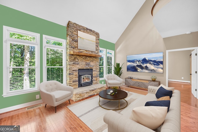 living area featuring high vaulted ceiling, visible vents, baseboards, and hardwood / wood-style flooring