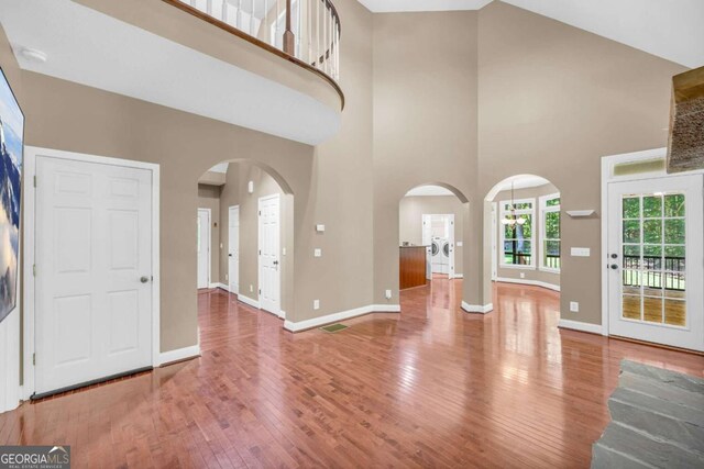 entryway featuring hardwood / wood-style flooring, high vaulted ceiling, and washer / clothes dryer