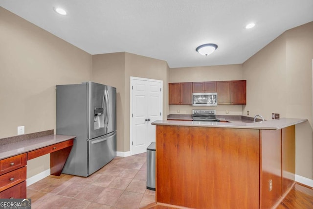 kitchen with stainless steel appliances, a peninsula, a sink, light countertops, and built in study area