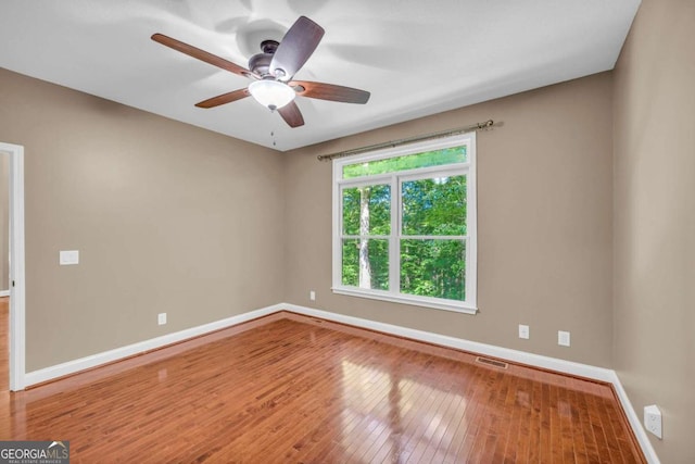 unfurnished room featuring wood-type flooring, visible vents, ceiling fan, and baseboards