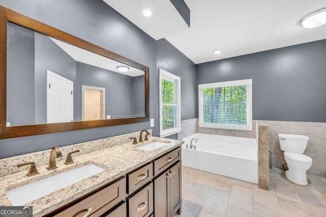 full bathroom with a garden tub, wainscoting, a sink, and toilet