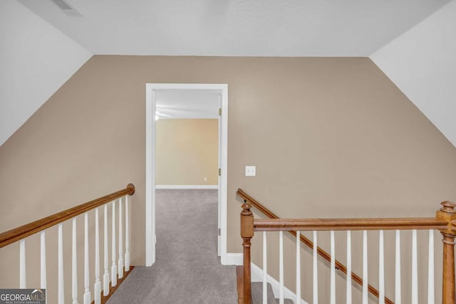 corridor with vaulted ceiling, visible vents, carpet, and an upstairs landing