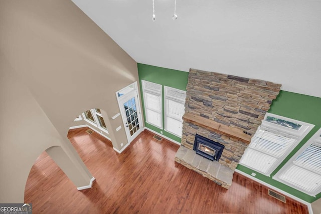 living room with a stone fireplace, high vaulted ceiling, and wood-type flooring