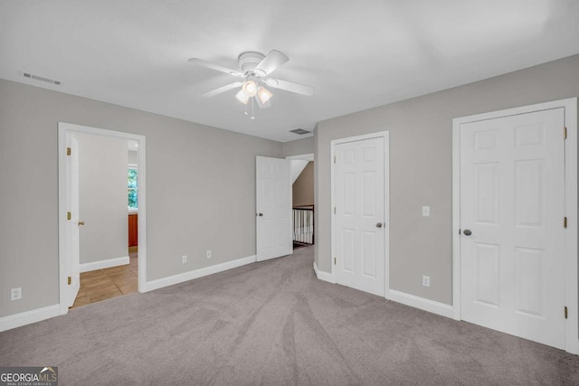 unfurnished bedroom with carpet floors, visible vents, baseboards, and ensuite bathroom