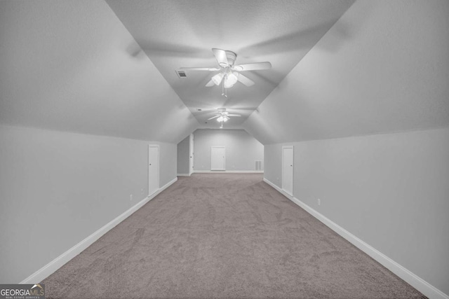 additional living space with visible vents, carpet flooring, vaulted ceiling, a textured ceiling, and baseboards