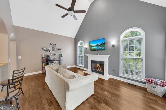 living room with dark hardwood / wood-style flooring, high vaulted ceiling, and ceiling fan