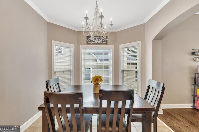 dining area with crown molding, a notable chandelier, and light tile patterned floors