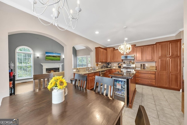 dining area with sink, a chandelier, light tile patterned floors, ornamental molding, and beverage cooler