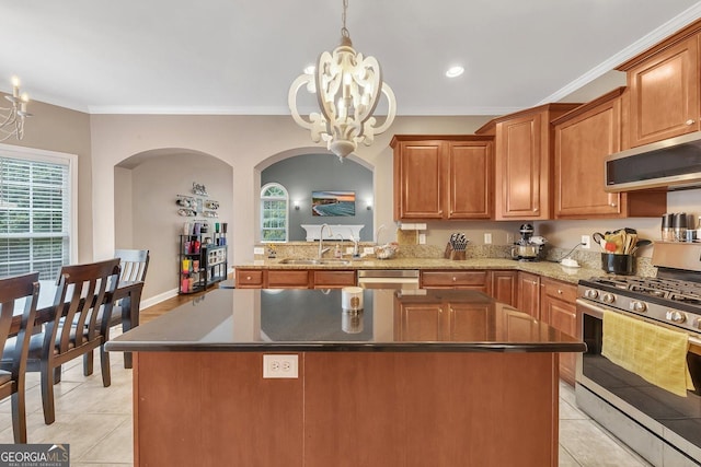 kitchen featuring pendant lighting, stainless steel appliances, a center island, ornamental molding, and a chandelier