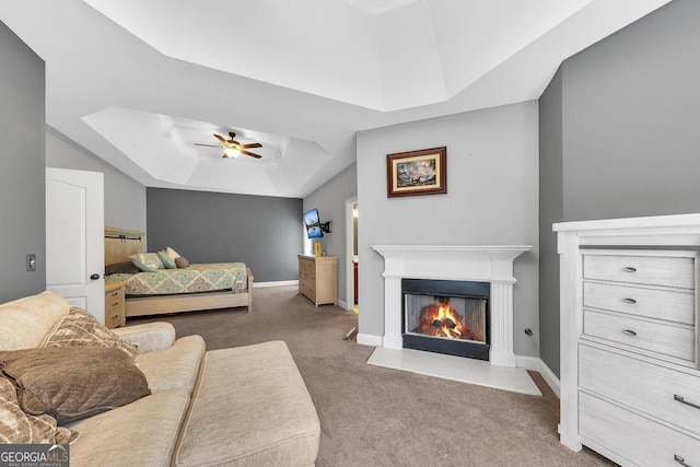 carpeted bedroom with ceiling fan and a tray ceiling