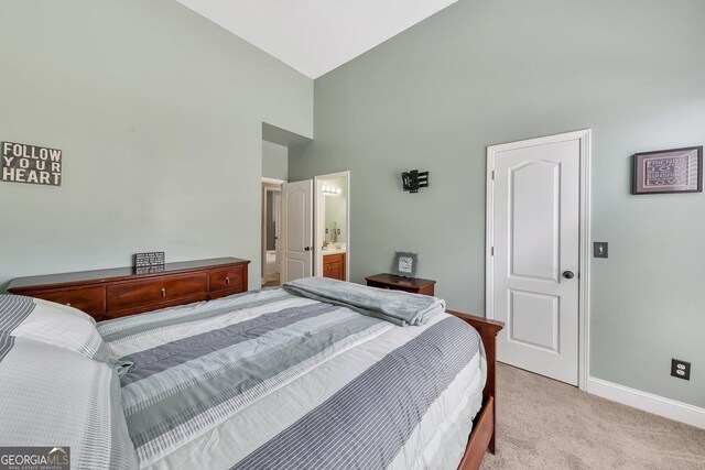 carpeted bedroom featuring connected bathroom and high vaulted ceiling