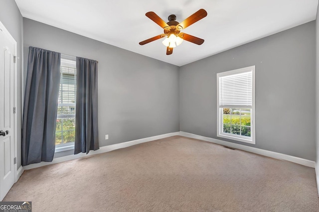 carpeted empty room featuring a wealth of natural light and ceiling fan