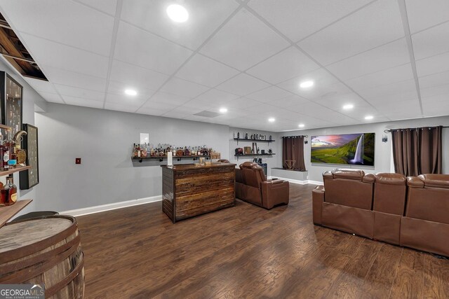 living room featuring dark hardwood / wood-style floors and a paneled ceiling