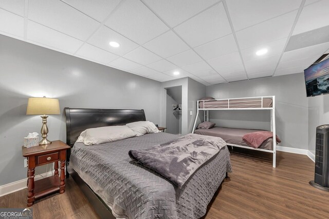 bedroom with dark hardwood / wood-style floors and a paneled ceiling