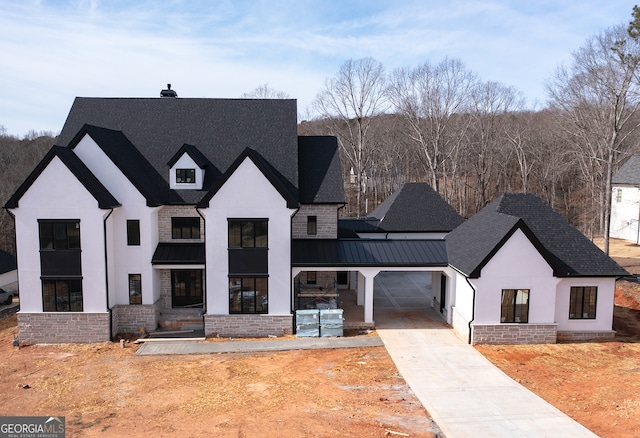 view of front of property with concrete driveway, metal roof, an attached garage, a standing seam roof, and stucco siding