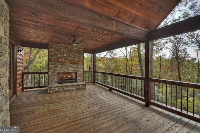 wooden terrace with an outdoor stone fireplace and ceiling fan