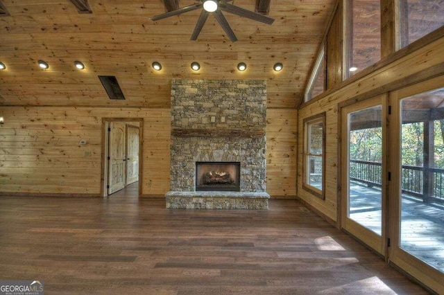 unfurnished living room with high vaulted ceiling, a fireplace, wood-type flooring, and wooden walls