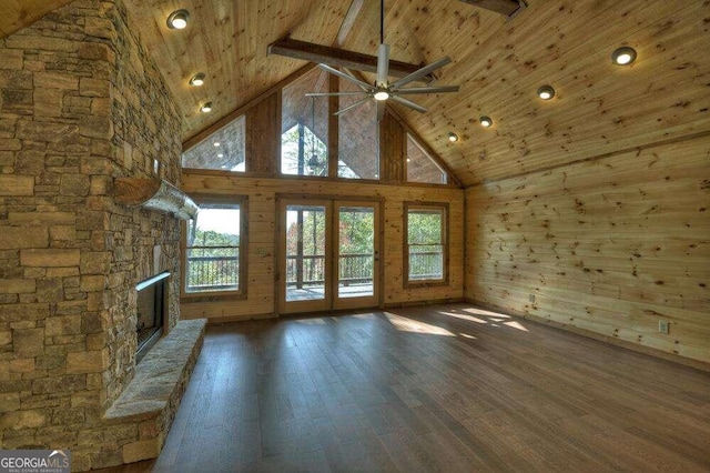 unfurnished living room with wood walls, high vaulted ceiling, a fireplace, and wood-type flooring