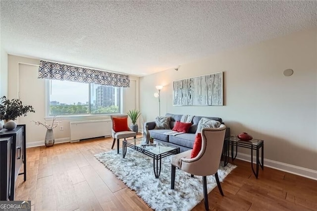 living room featuring wood-type flooring, radiator heating unit, and a textured ceiling