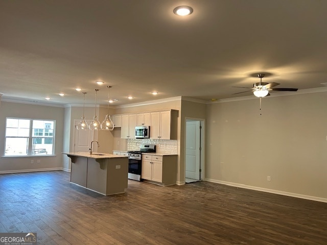 kitchen with dark hardwood / wood-style floors, decorative light fixtures, a center island with sink, appliances with stainless steel finishes, and ceiling fan