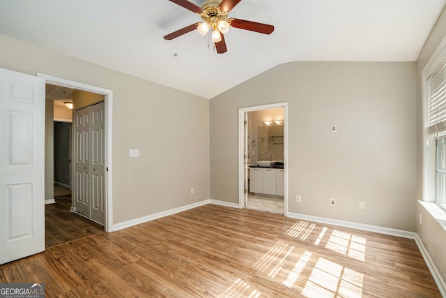 unfurnished bedroom featuring ensuite bathroom, hardwood / wood-style flooring, vaulted ceiling, and ceiling fan