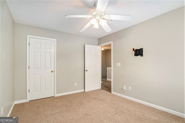 unfurnished bedroom with ceiling fan, carpet, and a textured ceiling