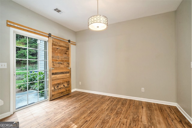 empty room with hardwood / wood-style flooring and a barn door