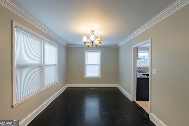 empty room featuring crown molding, hardwood / wood-style flooring, a chandelier, and a wealth of natural light