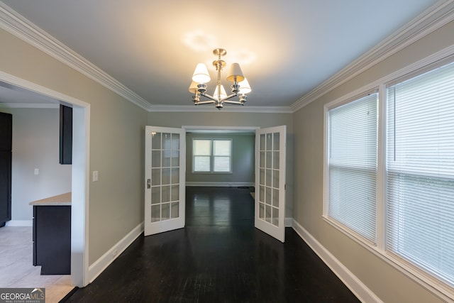 unfurnished dining area featuring crown molding, french doors, dark hardwood / wood-style flooring, and a chandelier