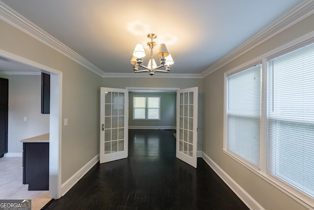 unfurnished dining area with crown molding, french doors, baseboards, and a chandelier