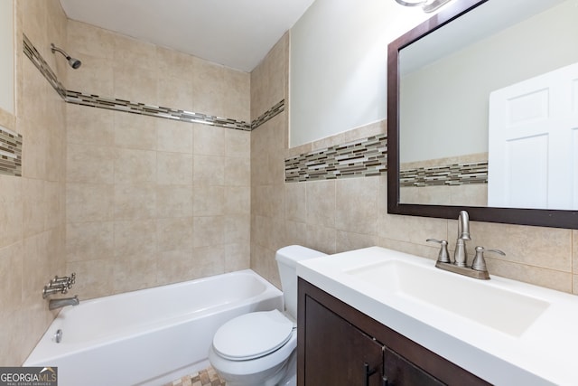 full bathroom featuring toilet, tiled shower / bath, vanity, tasteful backsplash, and tile walls