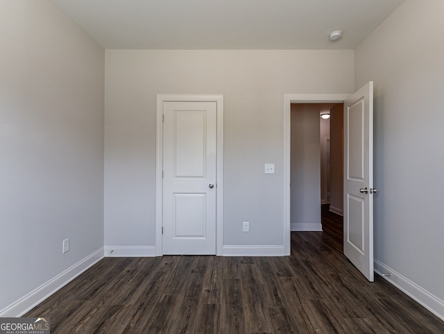 unfurnished bedroom with dark wood-type flooring and a closet