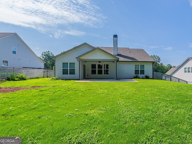 rear view of property featuring ceiling fan, a lawn, and a patio area