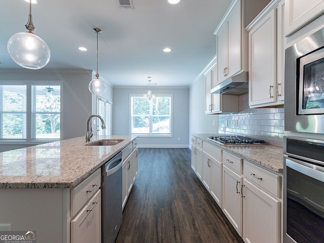 kitchen with dark hardwood / wood-style floors, a wealth of natural light, a kitchen island with sink, and ornamental molding