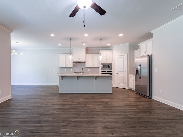 kitchen with appliances with stainless steel finishes, hanging light fixtures, white cabinets, decorative backsplash, and dark wood-type flooring